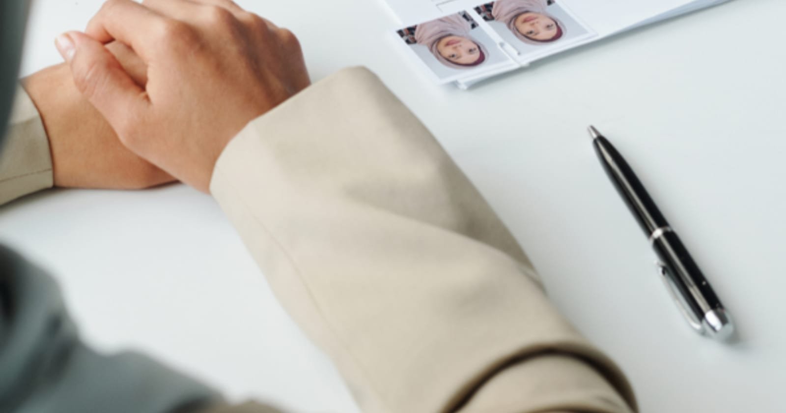 An application form being stamped across a desk, with passport photographs attached