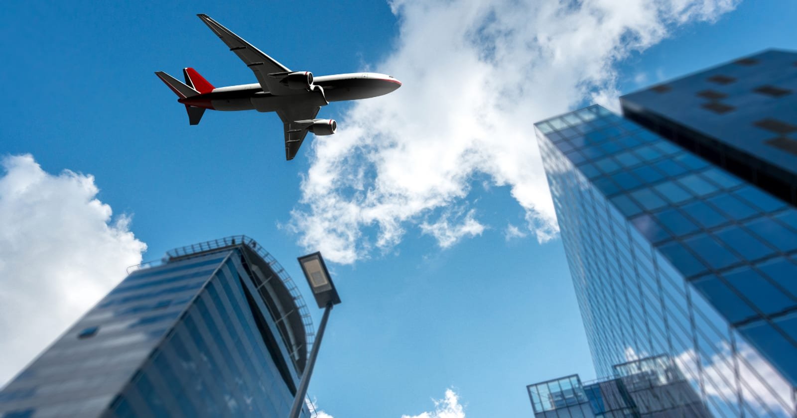 An airliner passing low above glass office towers